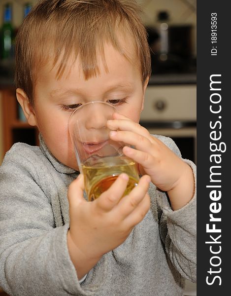 Young child holding glass of juice and drinking. Young child holding glass of juice and drinking