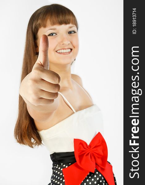 Beautiful Fashion Girl Smiling and showing thumb up. A look at the camera. Close-up. Black skirt with white polka dots. Topic white with a red bow at the waist. On a white background. Focus on foreground. Beautiful Fashion Girl Smiling and showing thumb up. A look at the camera. Close-up. Black skirt with white polka dots. Topic white with a red bow at the waist. On a white background. Focus on foreground.