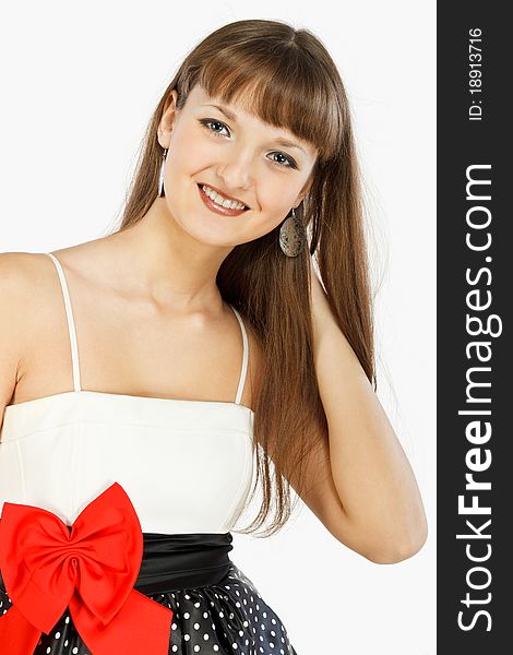 Beautiful Fashion Girl Smiling. Hand in hair. Black skirt with white polka dots. Topic white with a red bow at the waist. Close-up. On a white background.