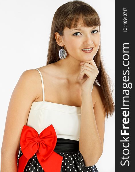 Beautiful Fashion Girl Smiling. Hand touches the chin. Black skirt with white polka dots. Topic white with a red bow at the waist. Close-up. On a white background.