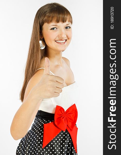 Beautiful Fashion Girl Smiling and showing thumb up. Close-up. A look at the camera. Black skirt with white polka dots. Topic white with a red bow at the waist. On a white background. Beautiful Fashion Girl Smiling and showing thumb up. Close-up. A look at the camera. Black skirt with white polka dots. Topic white with a red bow at the waist. On a white background.