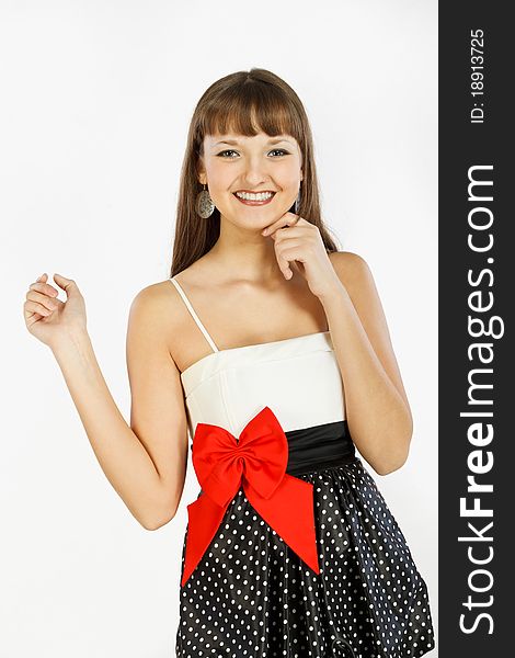 Showing, Giving Or Presenting. A look at the camera. Beautiful Fashion Girl Smiling. Black skirt with white polka dots. Topic white with a red bow at the waist. White background.