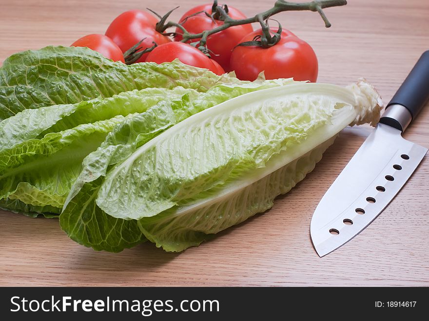 Fresh Romaine lettuce and ripe tomatoes on the wooden table, selective focus. Fresh Romaine lettuce and ripe tomatoes on the wooden table, selective focus.