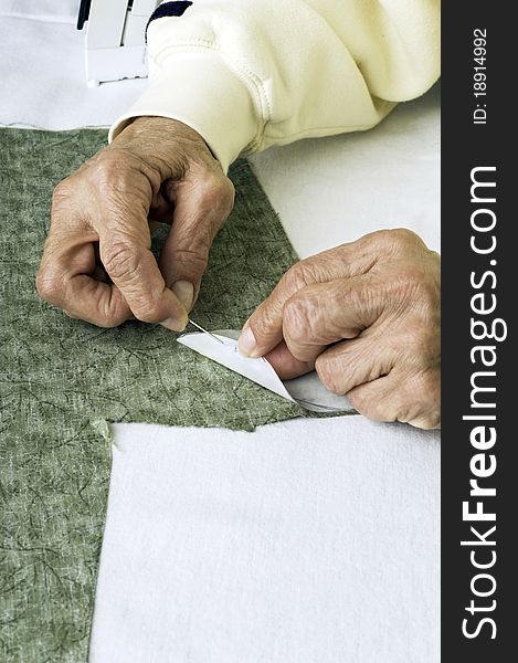 A quilter applies fabric glue to heat resistant plastic for leaf applique pattern. A quilter applies fabric glue to heat resistant plastic for leaf applique pattern.