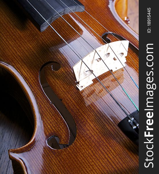 A close in shot of a violin on a wood background. A close in shot of a violin on a wood background