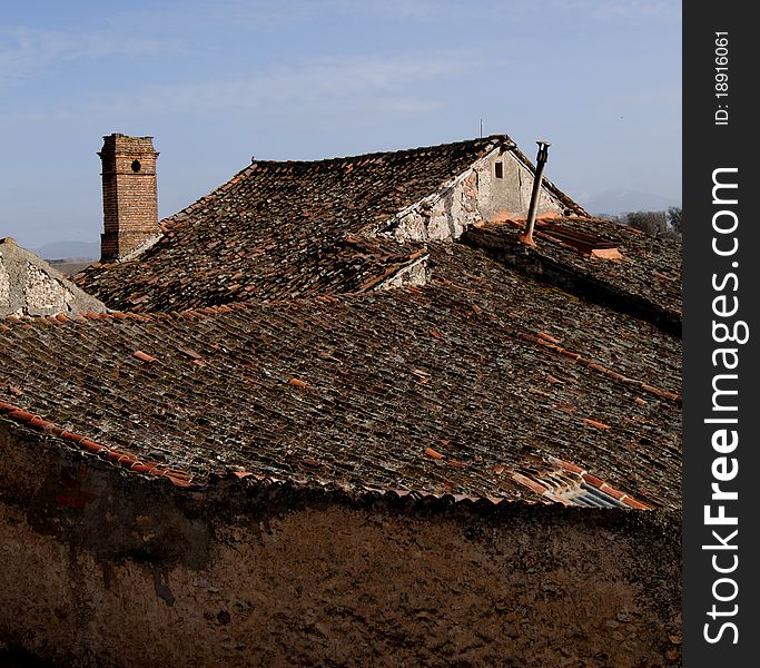 Old tiled roof, chimney and tower of a village. Old tiled roof, chimney and tower of a village