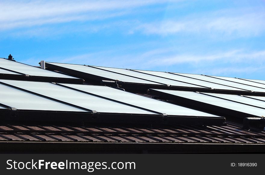 A group of solar panels on a roof on a sunny day. A group of solar panels on a roof on a sunny day.