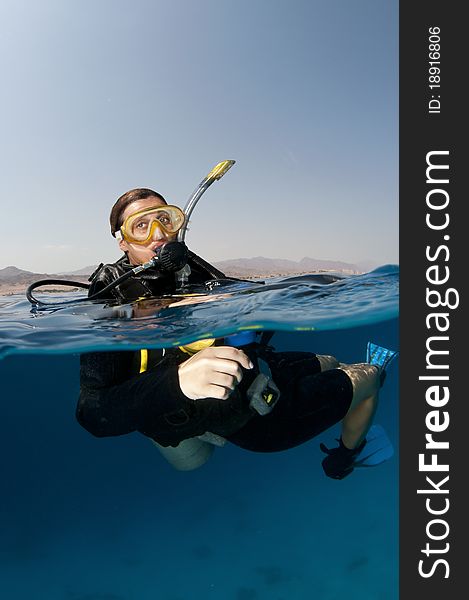 Over under shot of scuba diver just before dive. Over under shot of scuba diver just before dive