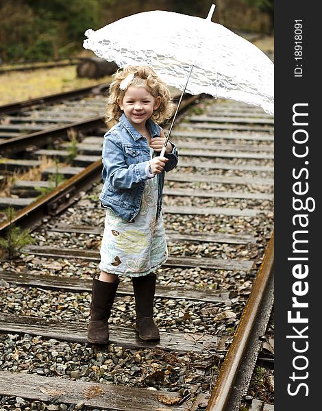 Young girl holding an umbrella while on a set of railroad tracks. Young girl holding an umbrella while on a set of railroad tracks