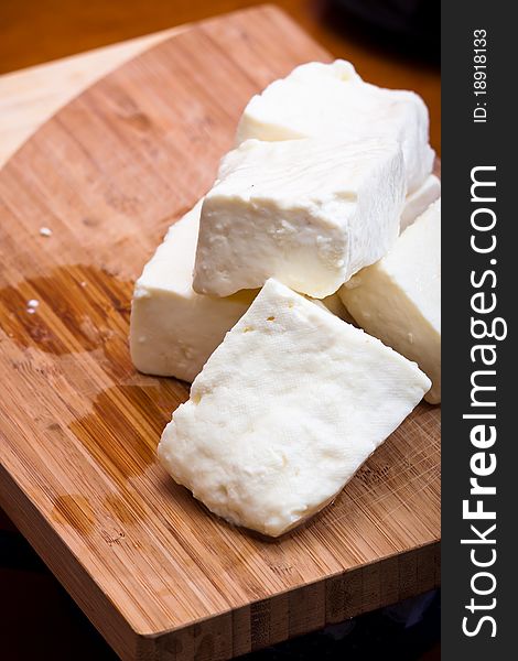 Big slices of Curd cheese on cutting board.