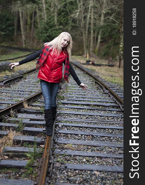 Beautiful young teenage girl sitting on her suitcase in the middle of railroad tracks. Beautiful young teenage girl sitting on her suitcase in the middle of railroad tracks.