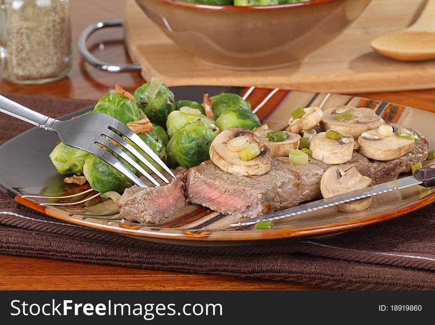 Cut piece of steak with mushrooms and brussels sprouts