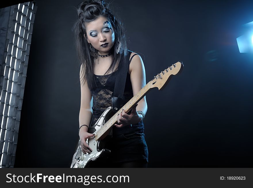 Woman rock star with guitar on dark background. Woman rock star with guitar on dark background