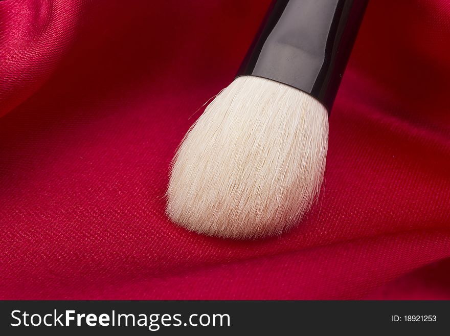 White brush for cosmetics on a red background.