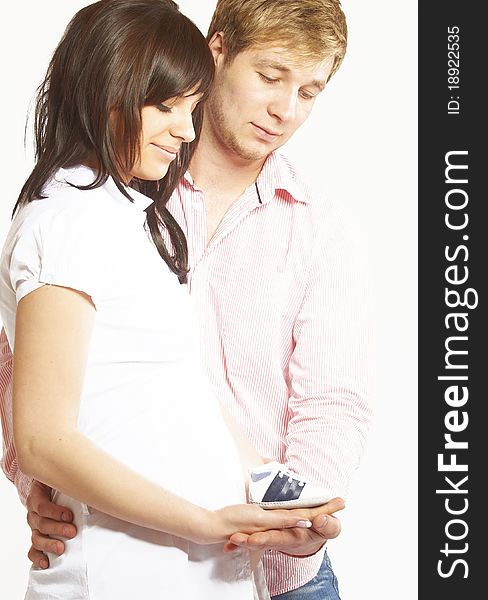 Portrait of a happy young couple, holding each other lovely with a baby shoe in their hands.They are smiling because they expecting a baby, image isolated on white background. Portrait of a happy young couple, holding each other lovely with a baby shoe in their hands.They are smiling because they expecting a baby, image isolated on white background