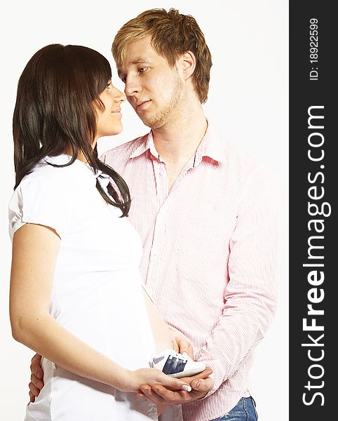 Portrait of a happy young couple, holding each other lovely with a baby shoe in their hands.They are smiling because they expecting a baby, image isolated on white background. Portrait of a happy young couple, holding each other lovely with a baby shoe in their hands.They are smiling because they expecting a baby, image isolated on white background