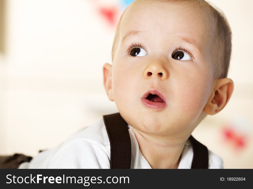 Sweet caucasian baby boy with white shirt and brown suspenders lying on floor and looking up innocently. Sweet caucasian baby boy with white shirt and brown suspenders lying on floor and looking up innocently.