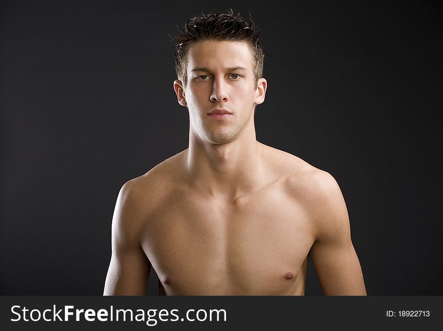 Young man poses in studio against a black backdrop. Young man poses in studio against a black backdrop.