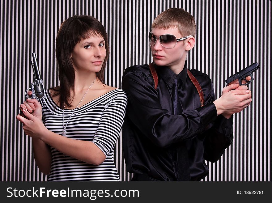 Young couple holding guns over stripe background