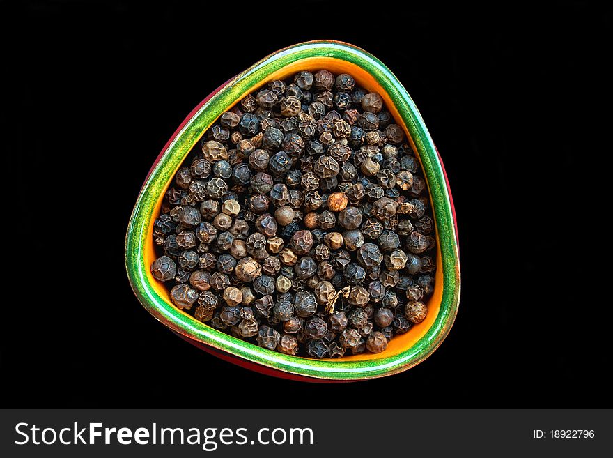 Black pepper in small ceramic bowl isolated on black background. Black pepper in small ceramic bowl isolated on black background