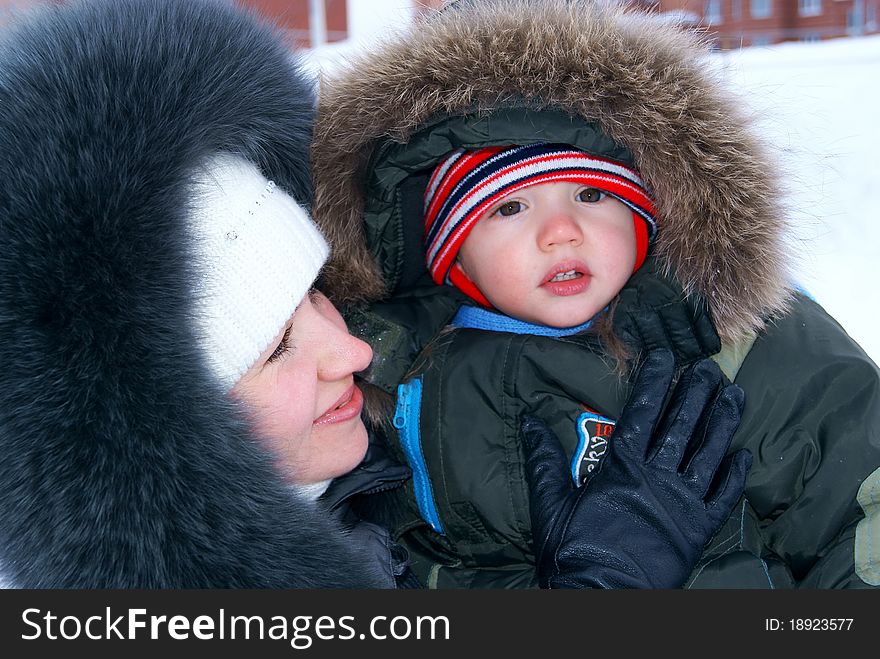 In the winter mother holds on hands of the child in winter clothes. In the winter mother holds on hands of the child in winter clothes