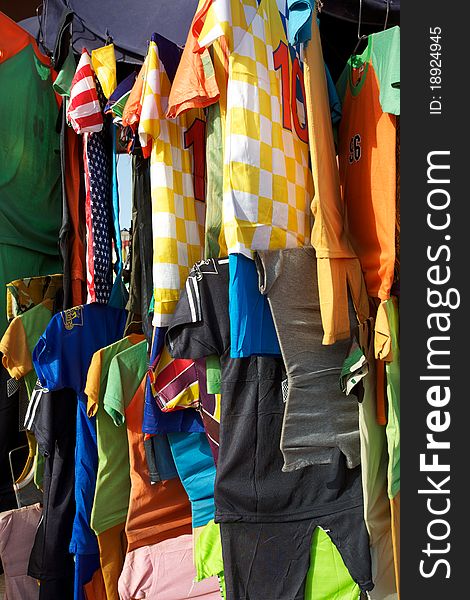 A selection of colorful t-shirts hanging on a rack in the market of Mopti in Mali