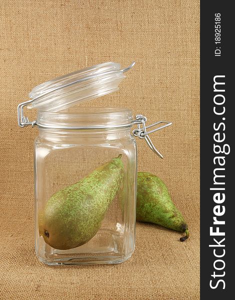 Pear in a glass jar on a jute background. Pear in a glass jar on a jute background