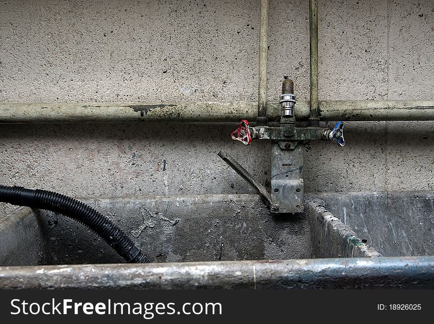 Piping, plumbing and faucet surrounding an industrial, concrete sink. Piping, plumbing and faucet surrounding an industrial, concrete sink.