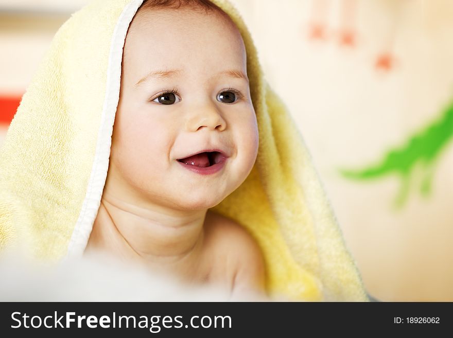 Close up of sweet laughing caucasian baby boy covered with yellow blanket lying on floor. Close up of sweet laughing caucasian baby boy covered with yellow blanket lying on floor.