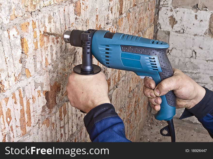 A man drilling a hole in the wall. A man drilling a hole in the wall.