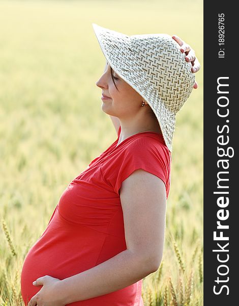 Happy pregnant woman in the summer wheat field