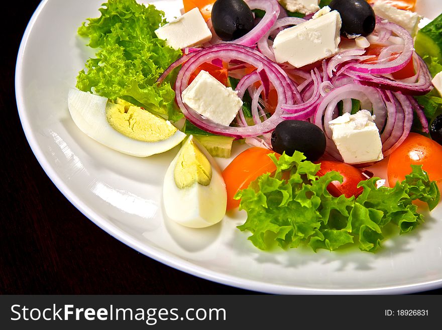 Salad from fresh vegetables, spinach, tomatoes, onions, olives, cheese and eggs