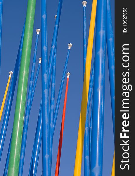 Colorful empty flagpoles against a clear blue sky