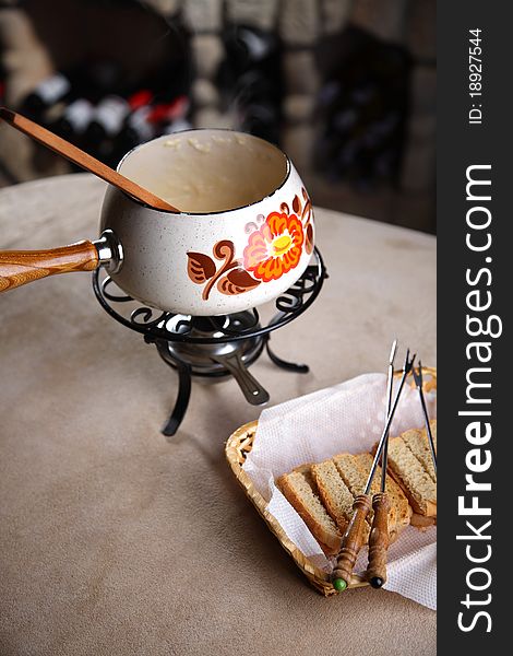 Fondue in a wine cellar. Crackers in a wattled basket with plugs
