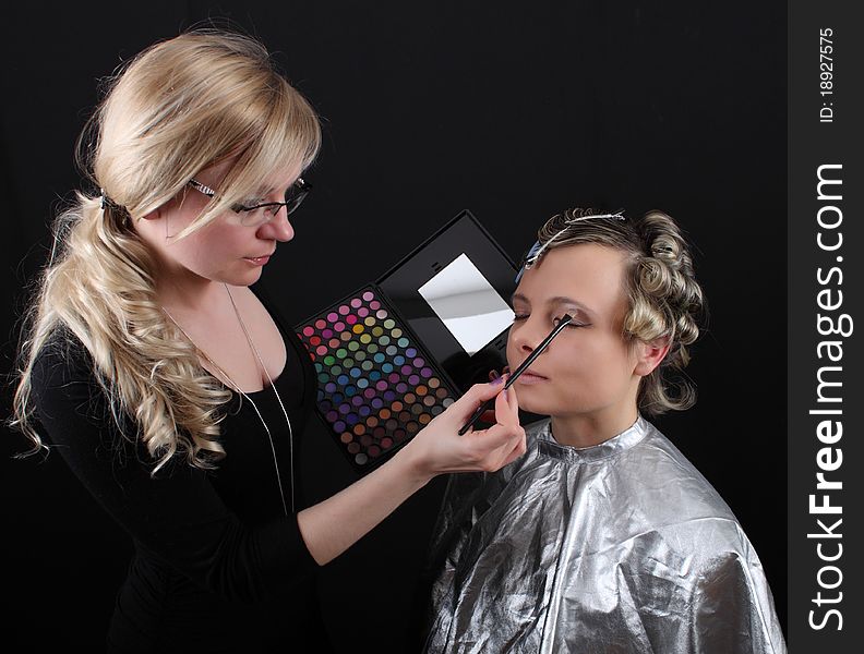 Stylist beautician does her hair and makeup, preparing model shooting