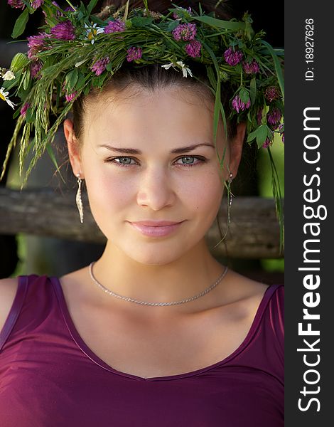 Portrait of the Beautiful young girl with a wreath from wild flowers on a head