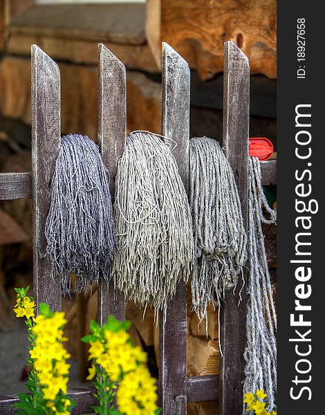 Three old mops on an old fence