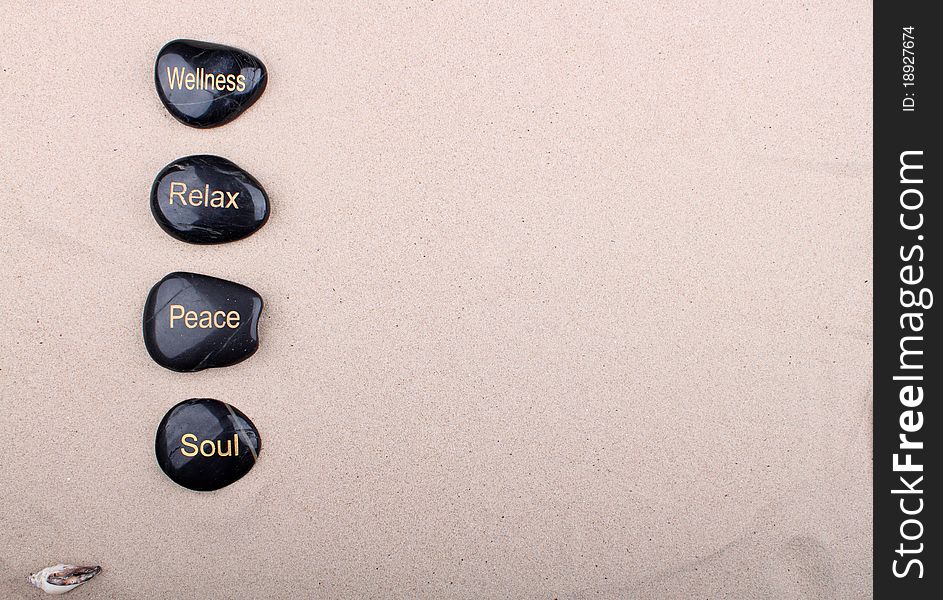 Four stones with gold letters lie on the sandy background