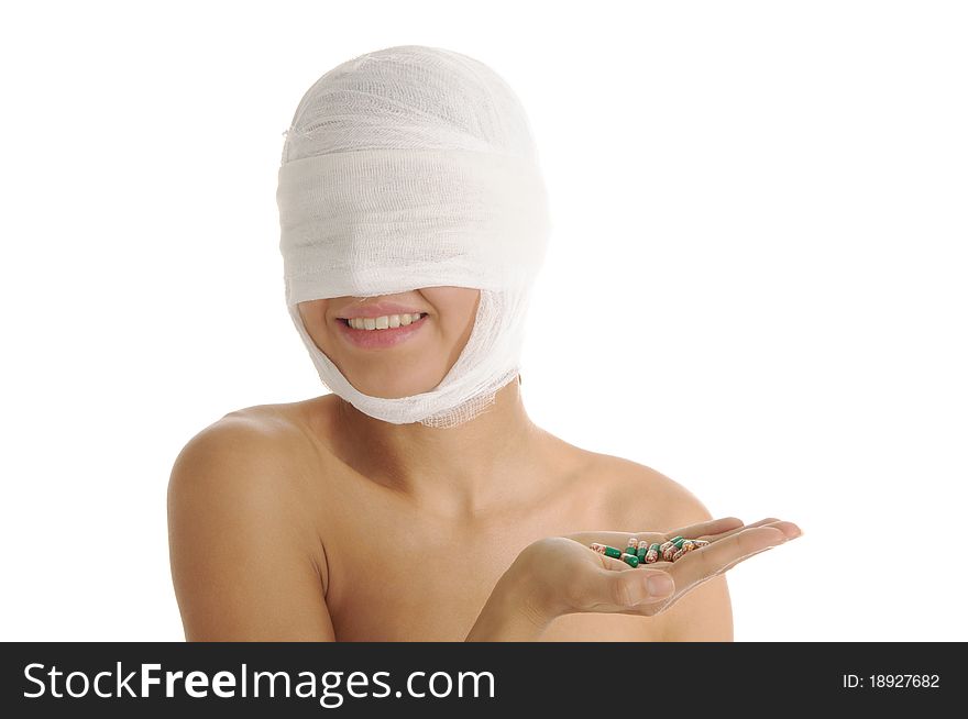 Woman with her head in bandages holding capsules in her hands isolated on white