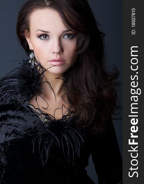 Portrait of the beautiful girl in a black velvet dress with wavy hair.