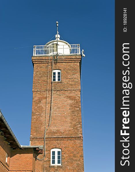 Lighthouse elevation made of red bricks at the blue sky background. Lighthouse elevation made of red bricks at the blue sky background.
