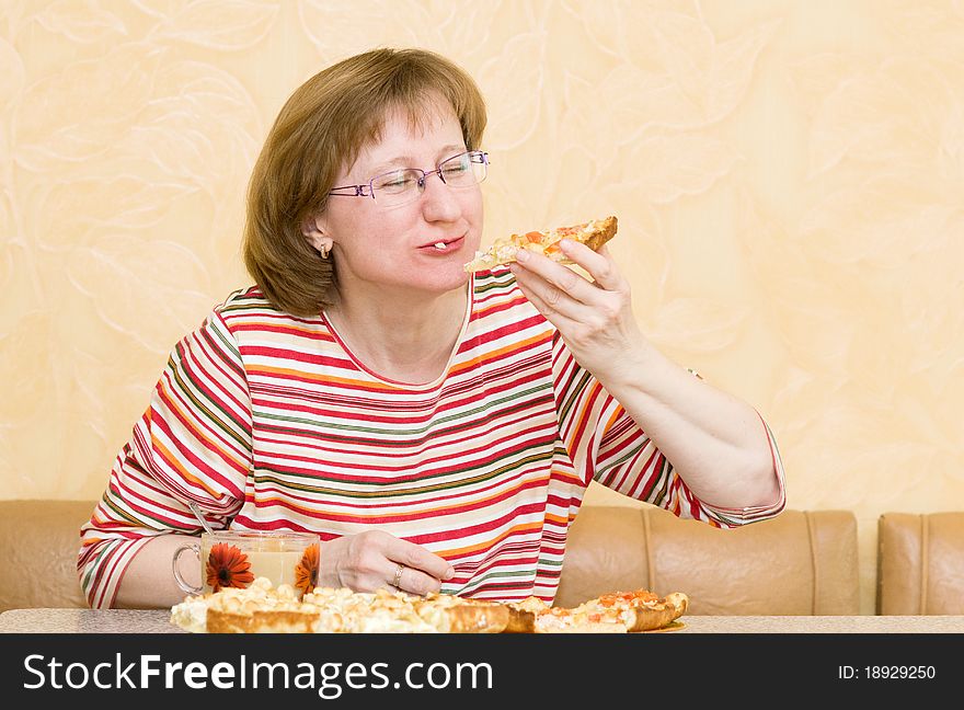 Elderly woman eating pizza at home