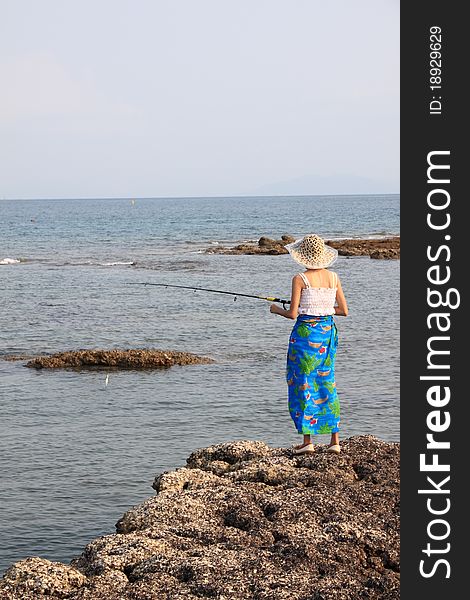 Girl fishing on the rock beach.