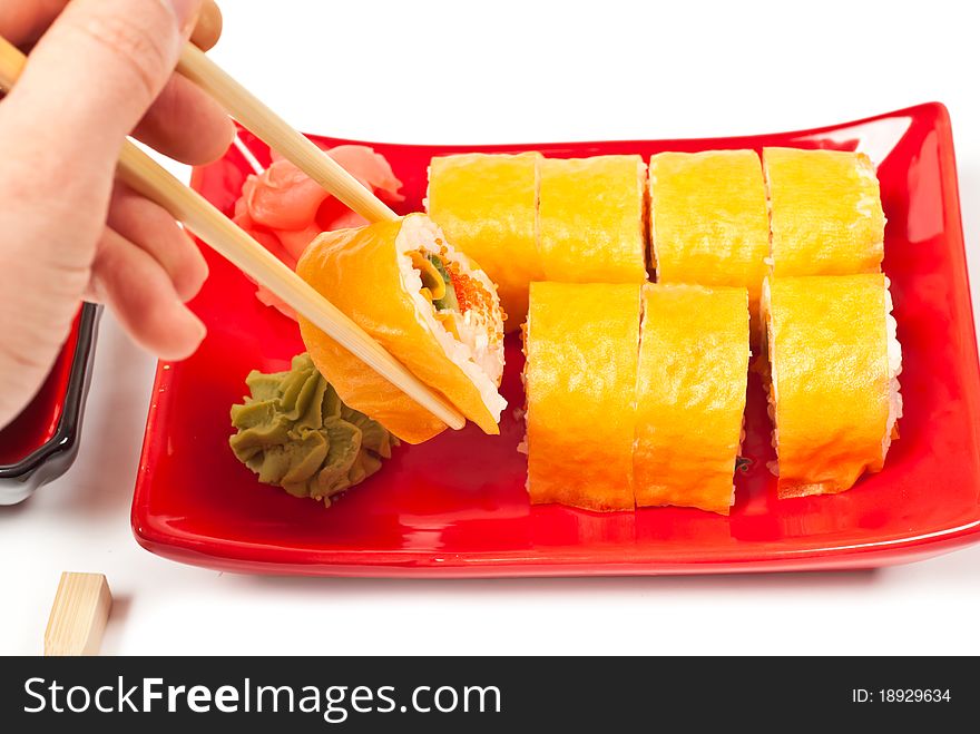 Men's hand holding sushi served on a plate. White background