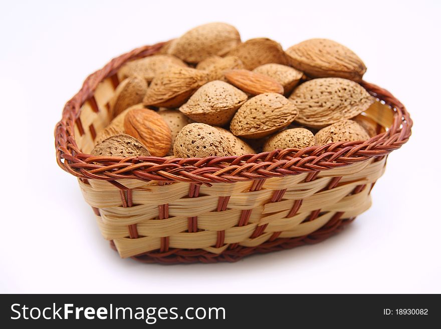 Fresh tasty almond nuts in wicker bowl isolated on white. Fresh tasty almond nuts in wicker bowl isolated on white