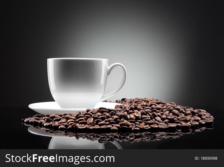 Photo of white cup with coffee beans on black