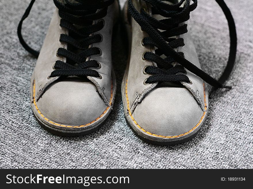 Winter shoes with yellow thread on gray background