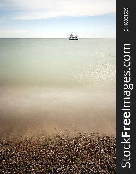 A long exposure day time wide angle photograph of the lake Ontario shore, with warm colors, and a ship at the horizon line. A long exposure day time wide angle photograph of the lake Ontario shore, with warm colors, and a ship at the horizon line.