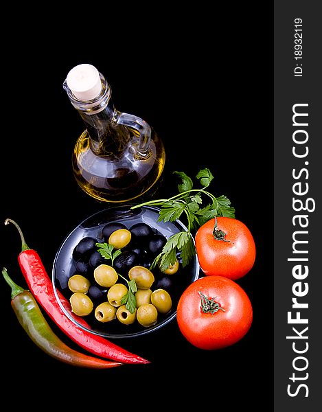 Olive oil, tomatoes, pepper and greens isolated on black