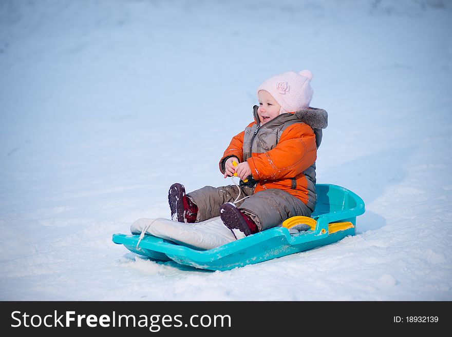 Adorable baby sliding on sleigh from hill